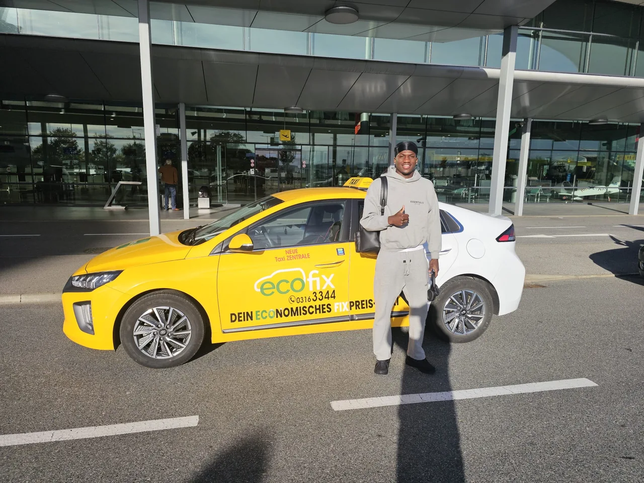Fahrgast vor einem EcoFix Taxi am Flughafen Graz