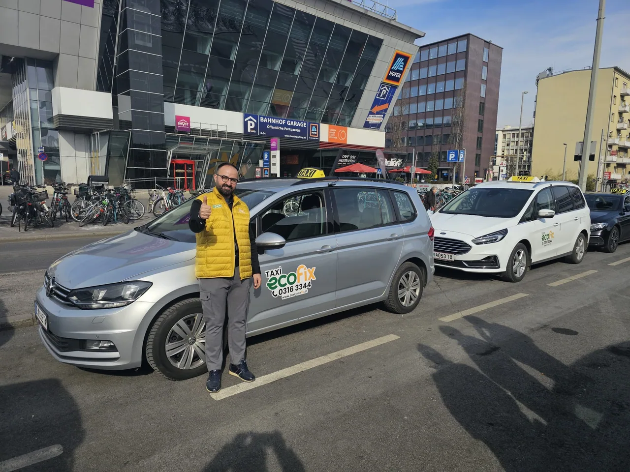 EcoFix Fahrer vor gebrandeten Taxis am Grazer Hauptbahnhof